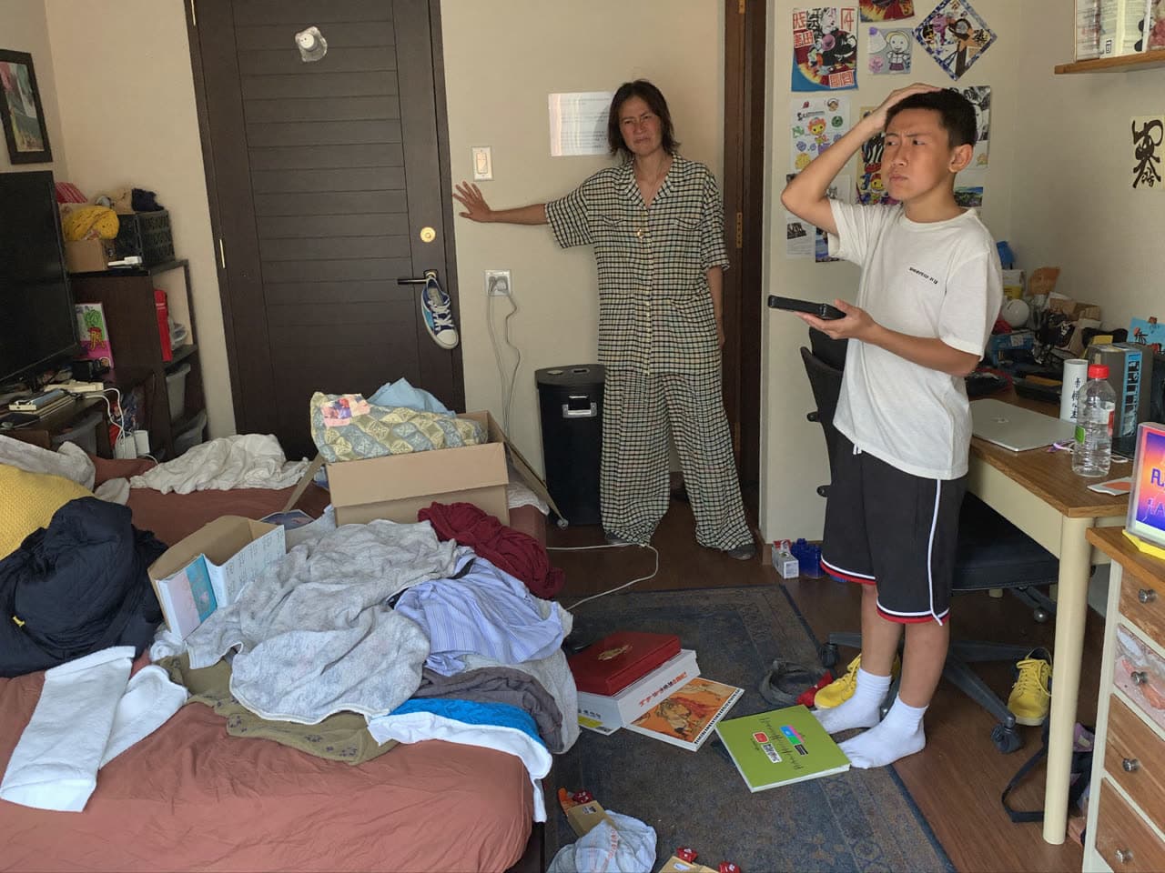 男孩的房间乱七八糟，妈妈皱着眉头指着房间，男孩不好意思地低头。